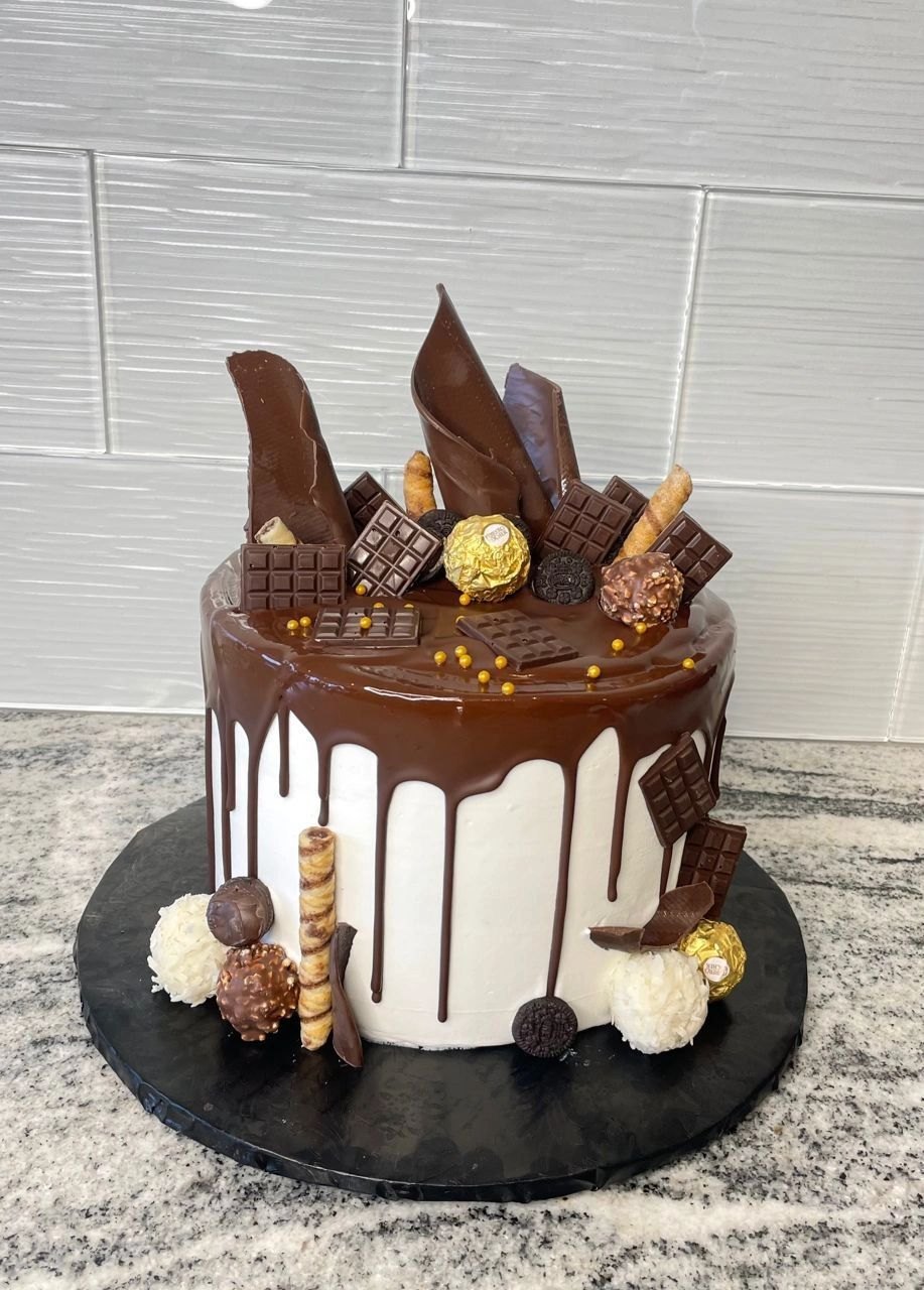 Chocolate drip cake decorated with chocolate shards, macarons and gold