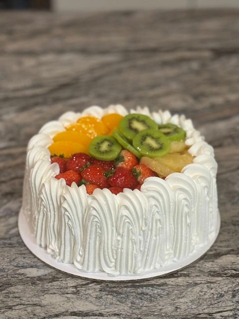 Whipped cream cake topped with kiwi, strawberries and mandarin