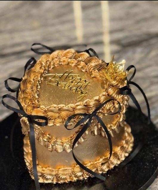Gold vintage piped cake finished with a black bow
