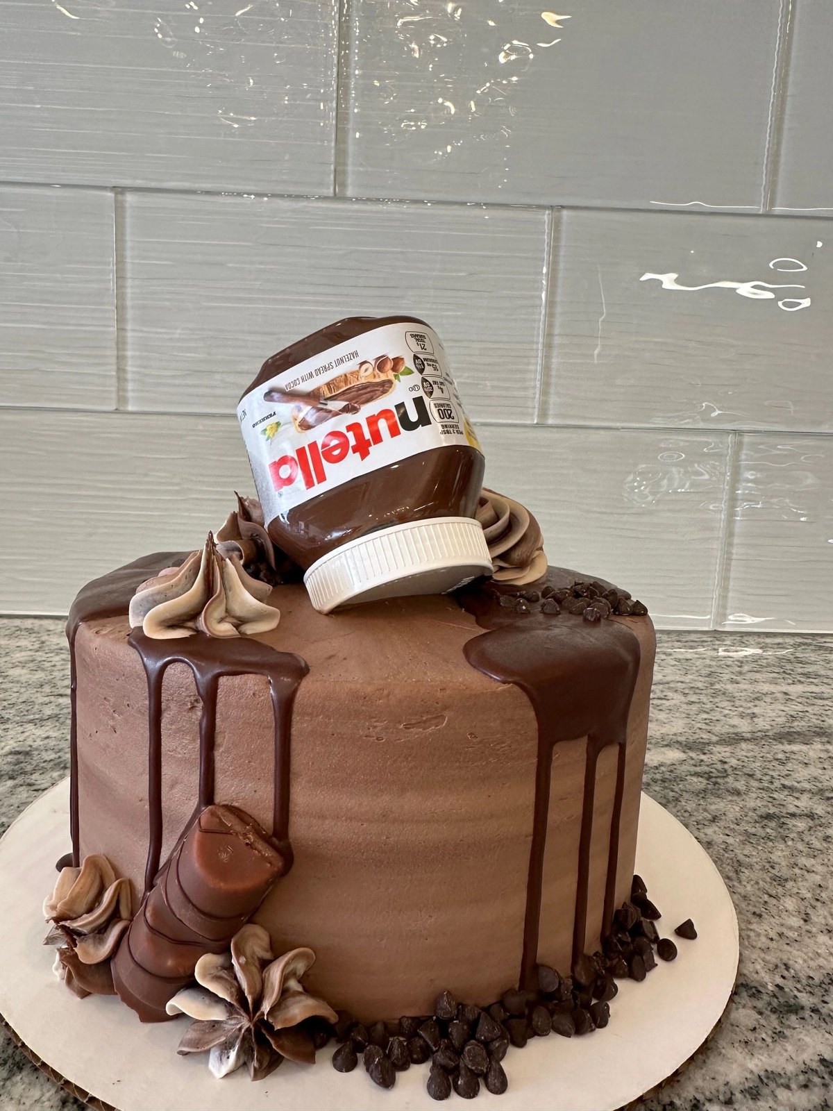 Chocolate drip cake topped with a Nutella jar and chocolate swirls