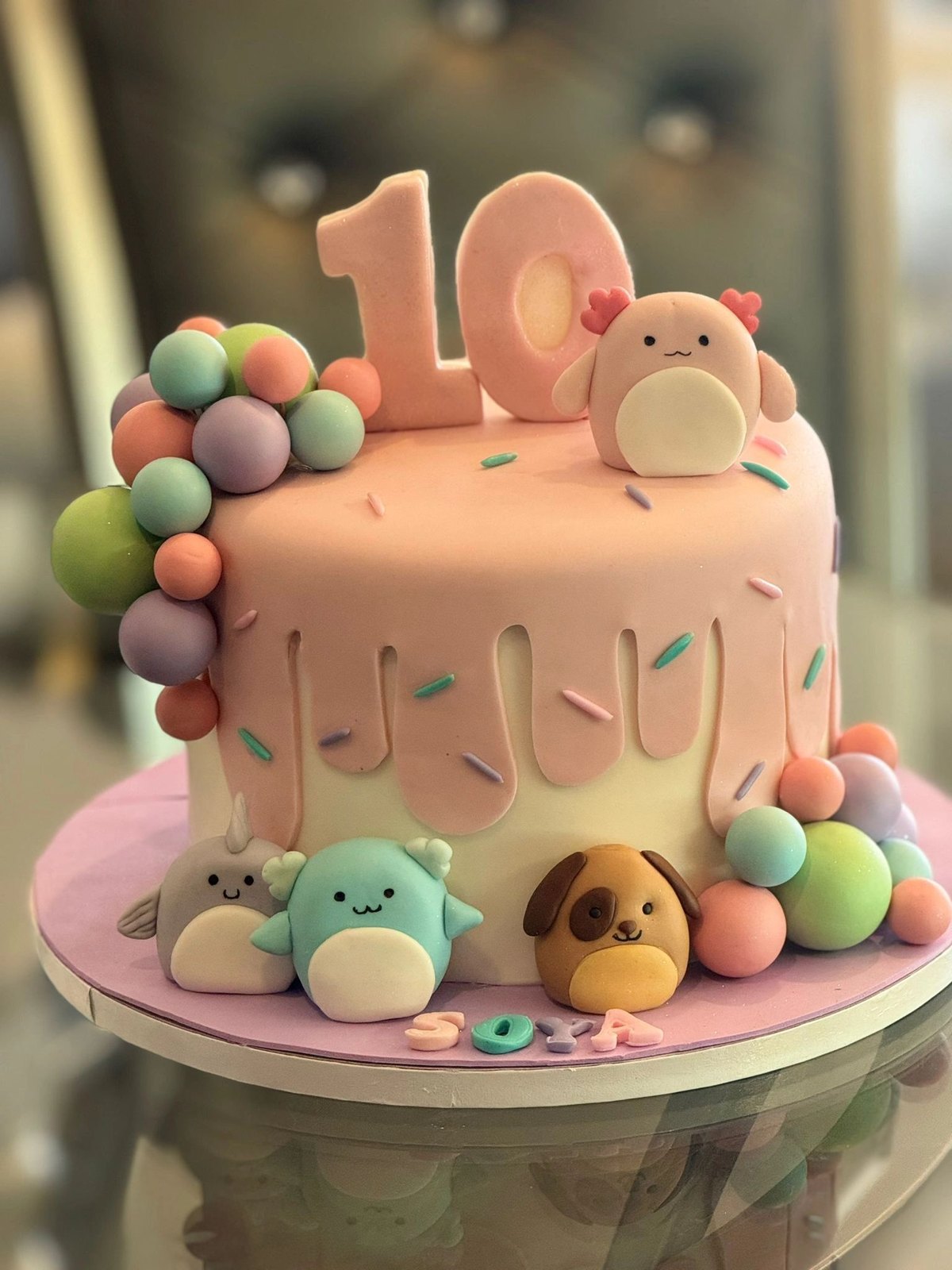 Pastel tenth-birthday cake decorated with plush toy characters