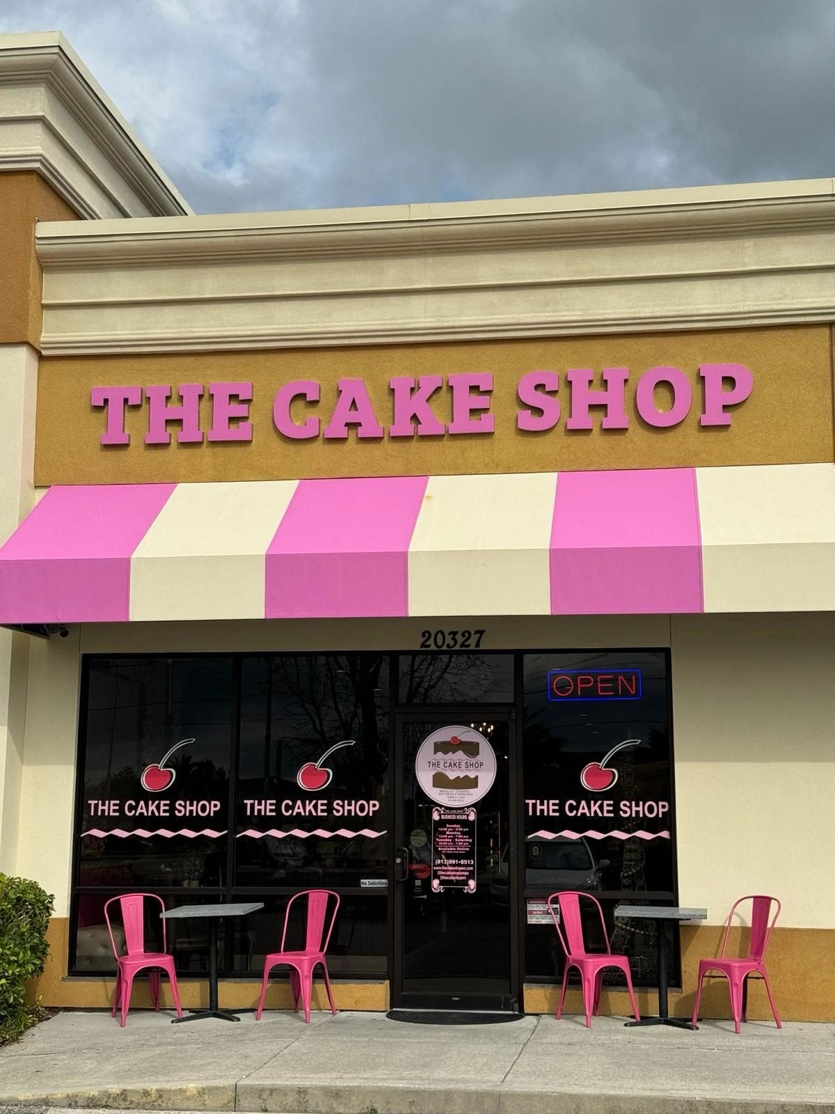 The Cake Shop storefront on Bruce B Downs Blvd with its pink and white striped awning and pink chairs