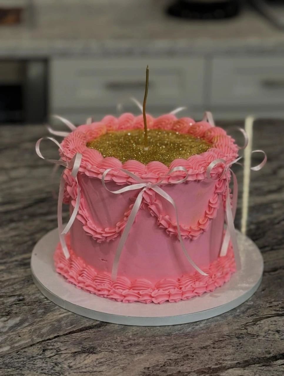 Pink vintage piped cake with ribbons and a gold glitter top